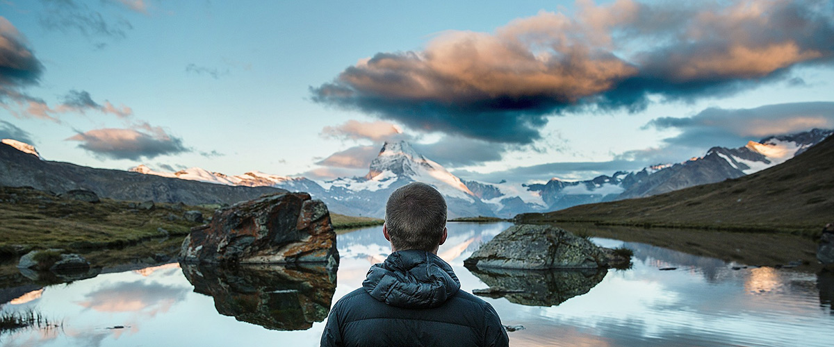 man looking at lake and mountains in the distance